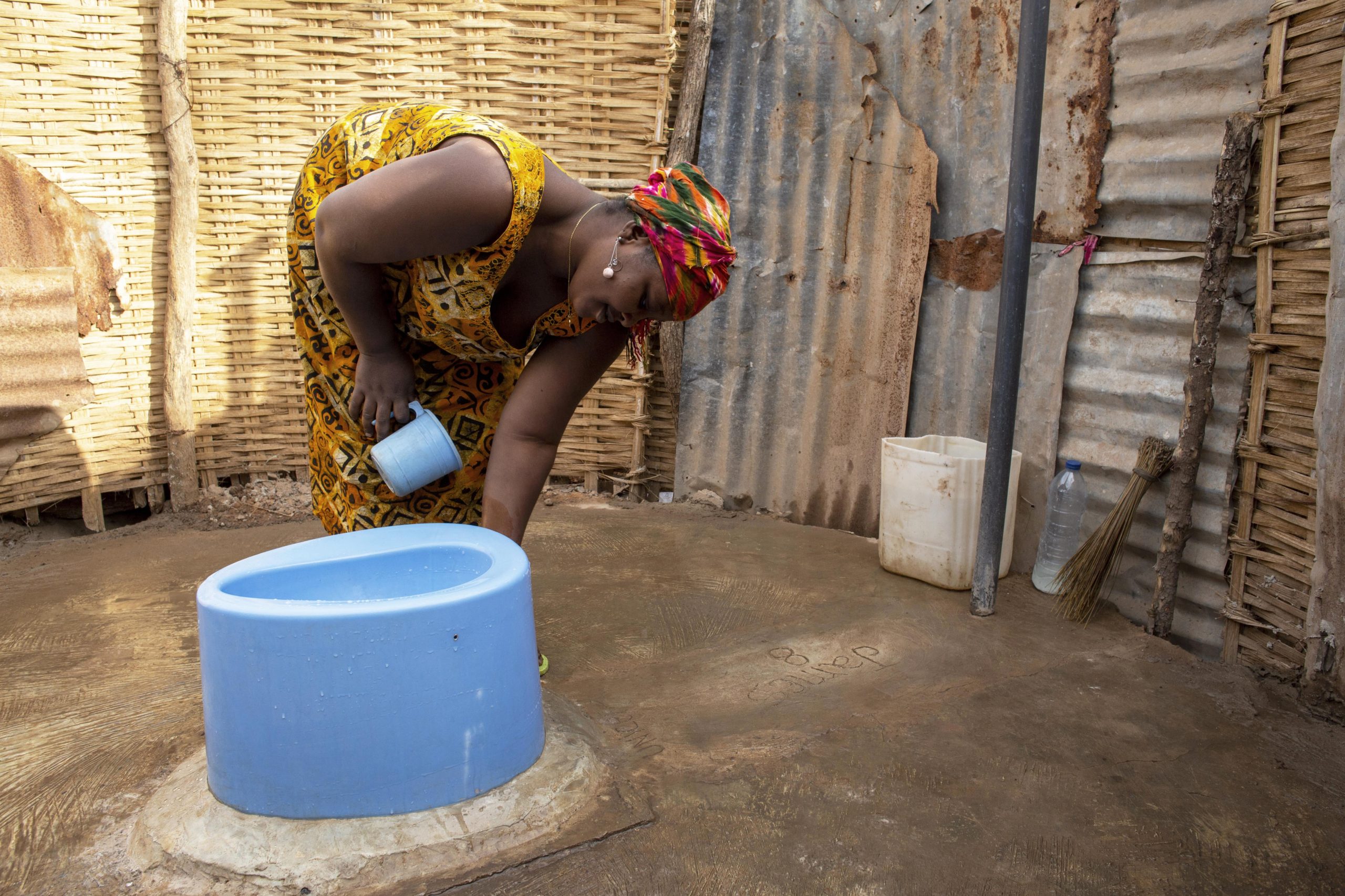 A woman cleans the area around the family's rehabilitated toilet in Guinea Bissau.