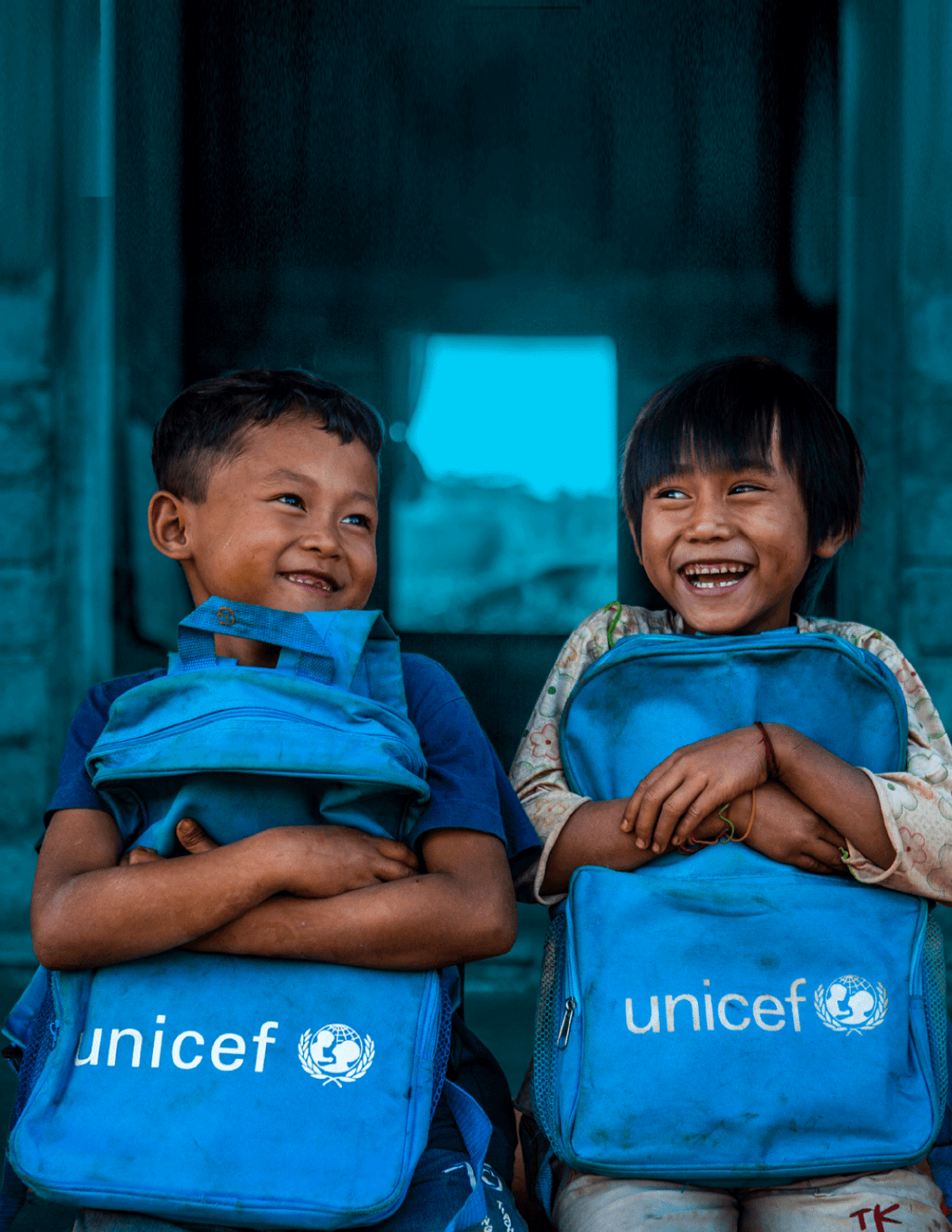 Two boys hold Unicef bag in front of their classroom in Myanmar.