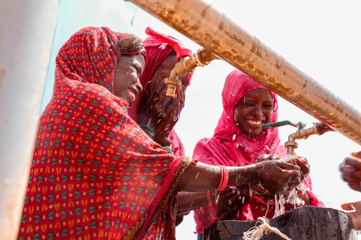 Children and adults collect water at a water facility in Africa.